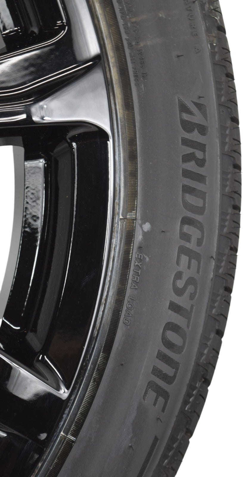 Close-up of a Bridgestone tire mounted on a black multi-spoke wheel, shown against a plain white background.