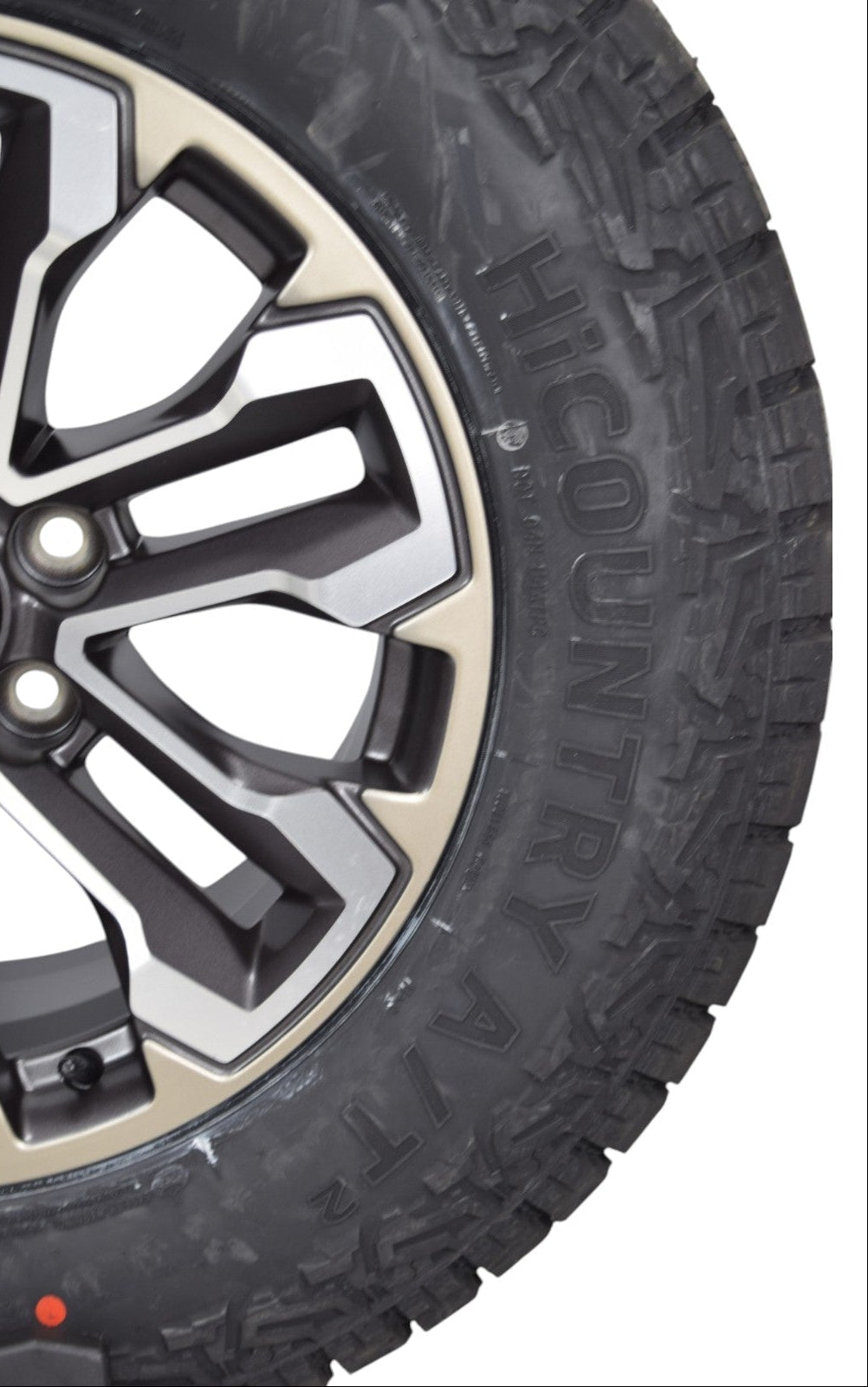 Close-up of a black off-road tire with aggressive tread and 'HICOUNTRY ATX' lettering, mounted on a multi-spoke black and silver wheel.
